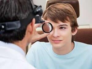 Image of an optometrist examining a teenage boy.