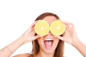Image of a woman holding lemons to her eyes and smiling.