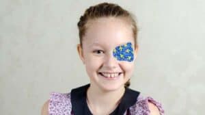 Image of a little girl wearing an eyepatch and smiling.