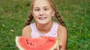 Image of a child with crossed eyes holding a watermelon.