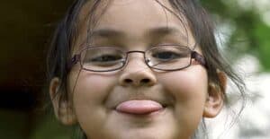 Image of girl wearing glasses and sticking tongue out.